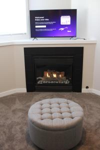 a living room with a fire place with a round ottoman at Freshly Updated 3 Bedroom Townhome in Lethbridge