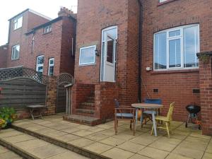 a patio with a table and chairs next to a brick building at 7 Cromwell Gardens - 2 Bed House in Scarborough