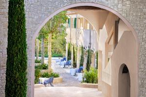 an archway leading to a patio with tables and chairs at Auberge La Coste in Le Puy-Sainte-Réparade
