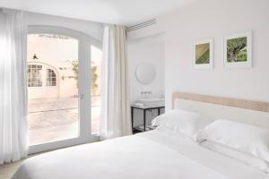 a white bedroom with a bed and a window at Auberge La Coste in Le Puy-Sainte-Réparade