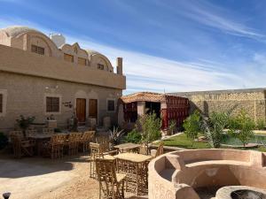 a patio with tables and chairs in front of a building at Agpeninshal Ecolodge in Siwa