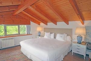 1 dormitorio con cama blanca y techo de madera en Hotel El Babú, en Caravia