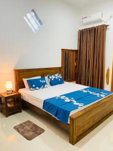 Schlafzimmer mit einem Bett mit blauer Bettwäsche und einem Tisch in der Unterkunft White Villa in Weligama