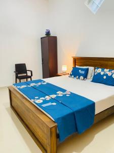 ein Schlafzimmer mit einem großen Bett mit blauer Bettwäsche und einem Stuhl in der Unterkunft White Villa in Weligama