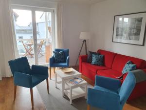 a living room with a red couch and two blue chairs at DAS APPARTEMENT INSELLIEBE RÜGEN inkl Sauna und 3h täglich Eintritt AHOI Schwimmbad in Ostseebad Sellin