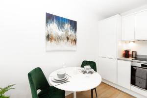 a white kitchen with a white table and green chairs at Stylish Studio Apt overlooking Old Trafford in Manchester