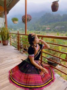 una joven sentada en una terraza mirando las montañas en Mai Anh Homestay - Pac Bo Village, 