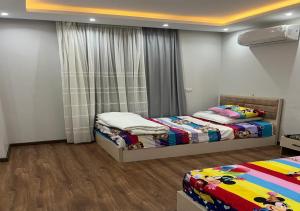 a bedroom with two beds and a window at شقه فندقيه مفروشه للأيجار في الكورت يارد in Sheikh Zayed