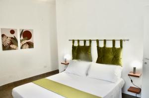 - une chambre avec un lit doté de draps blancs et d'oreillers verts dans l'établissement Villa Cossyra, à Porto Palo