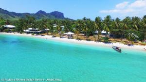 un bateau dans l'eau sur une plage avec des palmiers dans l'établissement Koh Mook Riviera Beach Resort, à Ko Muk