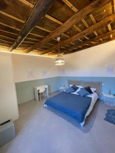 Un dormitorio con una cama azul y una mesa en Via Camerina 3, en Castelnuovo di Porto