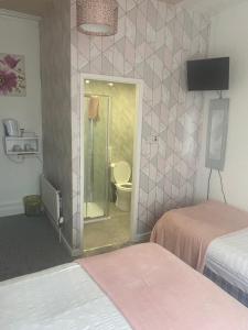a room with two beds and a bathroom with a toilet at The Cosy Nook in Blackpool