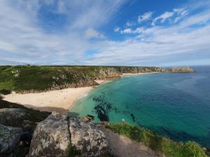 una persona seduta su una roccia vicino a una spiaggia di Primrose Cottage a Helston