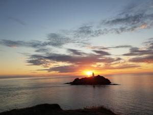 a lighthouse on an island in the ocean at sunset at Primrose Cottage in Helston