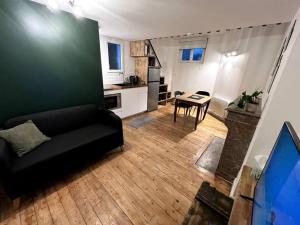 a living room with a black couch and a kitchen at Studio 2 - Mi-Côte - Duplex à Orvault in Orvault