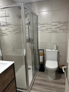 a bathroom with a toilet and a glass shower at Petite maison in Plouguerneau