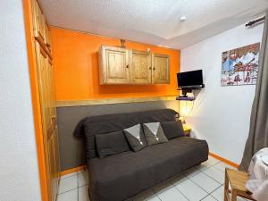 ein Sofa in einem Zimmer mit orangefarbener Wand in der Unterkunft Studio Samoëns, 1 pièce, 4 personnes - FR-1-624-115 in Samoëns