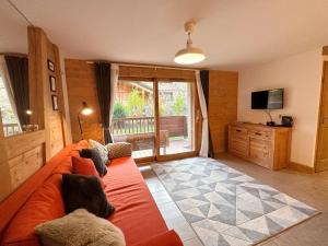 een woonkamer met een oranje bank en een televisie bij Appartement Samoëns, 3 pièces, 6 personnes - FR-1-624-16 in Samoëns