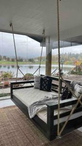 ein Schaukelbett in einem Zimmer mit Seeblick in der Unterkunft Your Magnificent Riverfront Home in Woodland