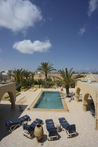 a swimming pool with lounge chairs and a swimming poolvisor at Dar Almassa in Mellita