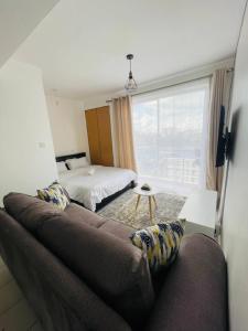 a bedroom with a couch and a bed and a window at One Bedrooms & Studios at Ngong Rd in Nairobi +29 photos