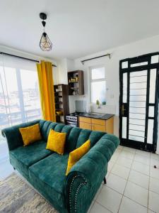 a green couch in a living room with yellow pillows at One Bedrooms & Studios at Ngong Rd in Nairobi