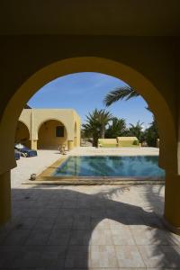 ein Torbogen, der zu einem Pool in einem Haus führt in der Unterkunft Dar Almassa in Mellita