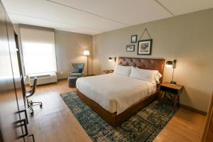 a bedroom with a bed and a chair and a window at Four Points by Sheraton Wakefield Boston Hotel & Conference Center in Wakefield