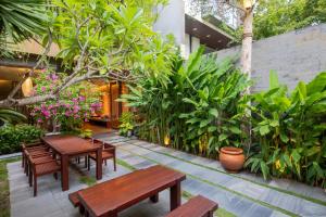a patio with wooden benches and plants at K-House vs Apartment in Danang