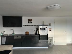 a kitchen with black and white cabinets and appliances at Ferienwohnung Annashome in Maxhütte-Haidhof