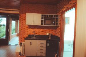 cocina con fregadero y pared de ladrillo en Villa Dal Maso en Campos do Jordão