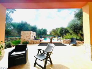 een patio met 2 stoelen en een zwembad bij All'ombra degli Ulivi by BarbarHouse in Latiano