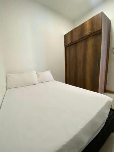um quarto com uma cama branca e um armário de madeira em Condominio Paraíso del Sol em San Jerónimo