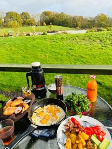 Hadlow Down的住宿－Peaceful ensuite lakeside cabin 'Tench'，一张桌子,上面有鸡蛋和蔬菜的早餐