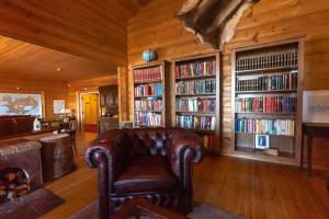ein Wohnzimmer mit einem Ledersessel und Bücherregalen mit Büchern in der Unterkunft Hotel Breiddalsvik in Breiðdalsvík