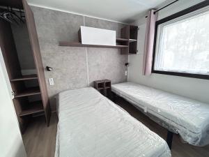 Una pequeña habitación con dos camas y una ventana. en Mobil home de 44m2, en La Palmyre 31 fotos más