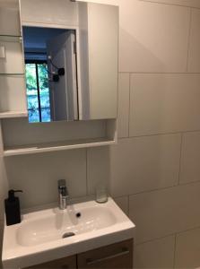 ein weißes Badezimmer mit einem Waschbecken und einem Spiegel in der Unterkunft La cabane du pêcheur - Lodges de Bonfruit 