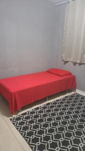 um quarto com uma cama vermelha e um tapete preto e branco em Família BRUMAR Condomio Dellos no Rio de Janeiro