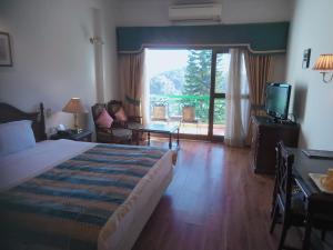 a hotel room with a bed and a sliding glass door at Kasauli Resort by Piccadily in Kasauli