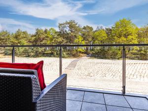 - un balcon avec une chaise et un oreiller rouge dans l'établissement FeWo Prora - Strandjuwel, à Binz