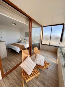 a room with two chairs and a bed and windows at Departamentos en la PLAYA in La Serena