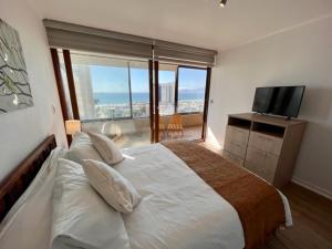 a bedroom with a large bed and a television at Departamentos en la PLAYA in La Serena