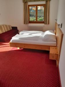 Cama grande en habitación con alfombra roja en Landgasthof Sonnegghof, en Castelvecchio