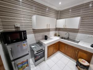 a small kitchen with white appliances and wooden cabinets at Keur Coumba in Dakar