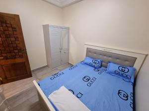 Schlafzimmer mit einem Bett mit blauer Bettwäsche und Kissen in der Unterkunft Keur Coumba in Dakar