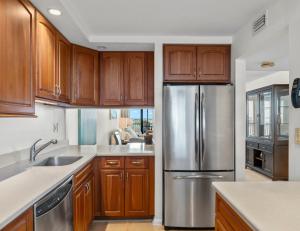 La cuisine est équipée d'armoires en bois et d'un réfrigérateur en acier inoxydable. dans l'établissement Palms Of Bay Beach 4f, à Fort Myers Beach
