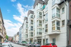 a tall white building on a street with parked cars at Federnest - Superior-2-Zimmer-Wohnung - Kingsize Boxspringbett - Home-Office mit Monitor - 11 Min Hbf in Duisburg