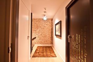 a hallway with a brick wall and an open door at Georgia's Bathhouse in Breda