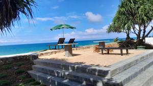 2 Stühle und ein Tisch mit Sonnenschirm am Strand in der Unterkunft Sevenra Grand Beach Hotel in Ambalangoda