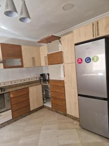 een keuken met een roestvrijstalen koelkast en houten kasten bij centre d'affaire in Zemmour Touirza